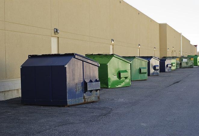 tilted front-load dumpsters being emptied by waste management workers in Goodwell